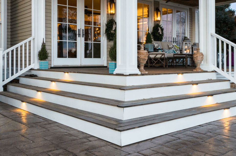 A porch with steps and lights on the side of it.