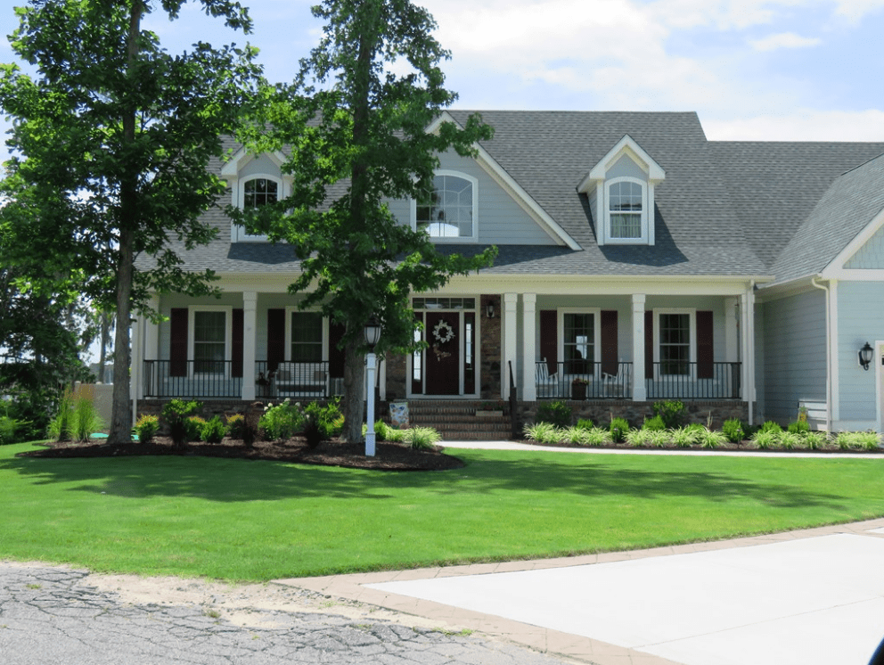 A large house with lots of green grass on the front lawn.