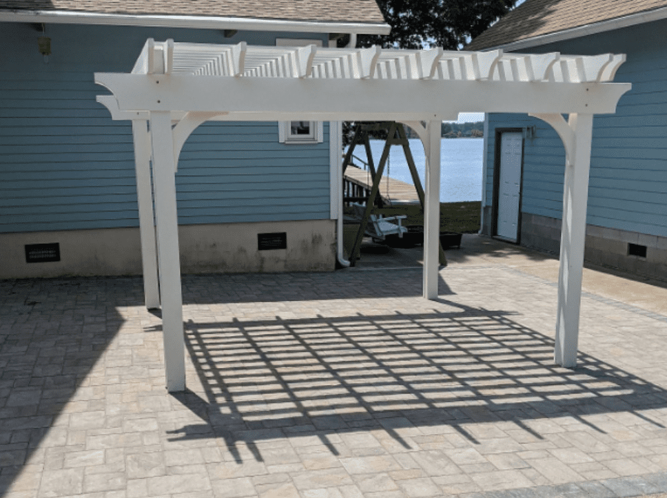 A white pergola sitting in the middle of a brick patio.