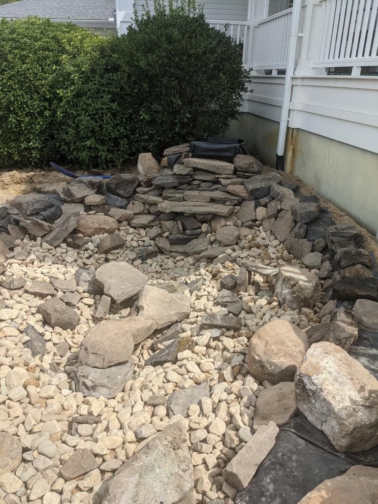 A pile of rocks in the ground next to a bush.