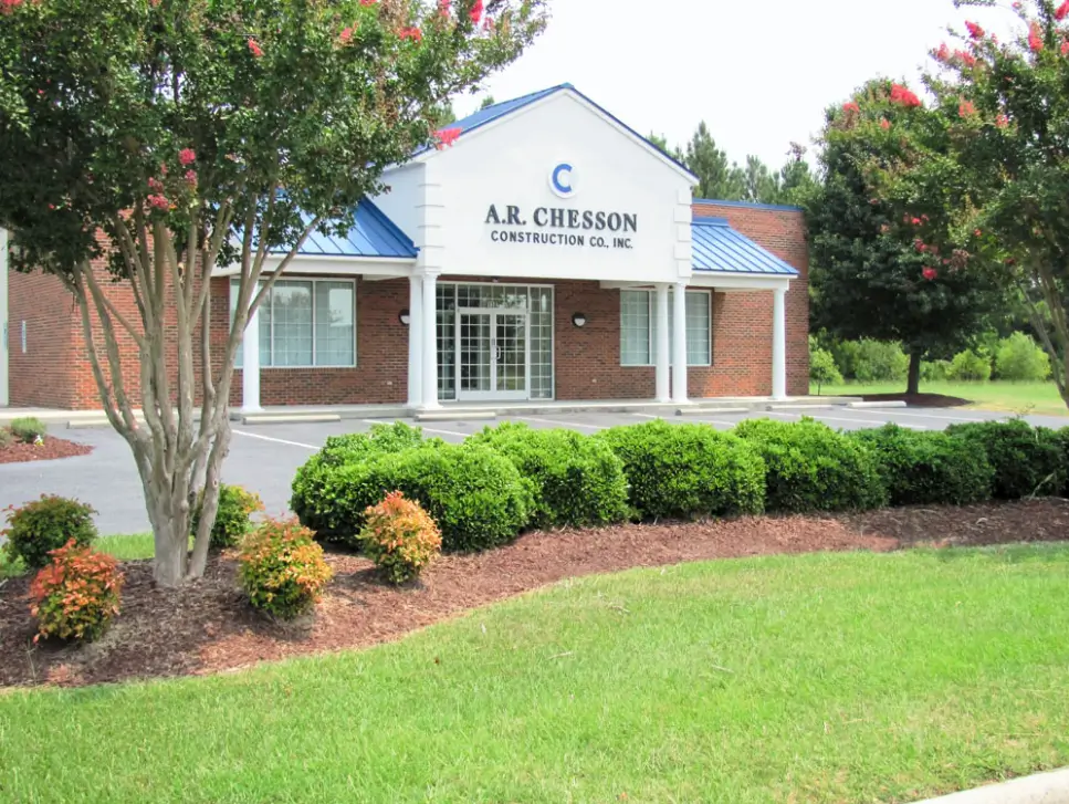 A building with bushes and trees in front of it.