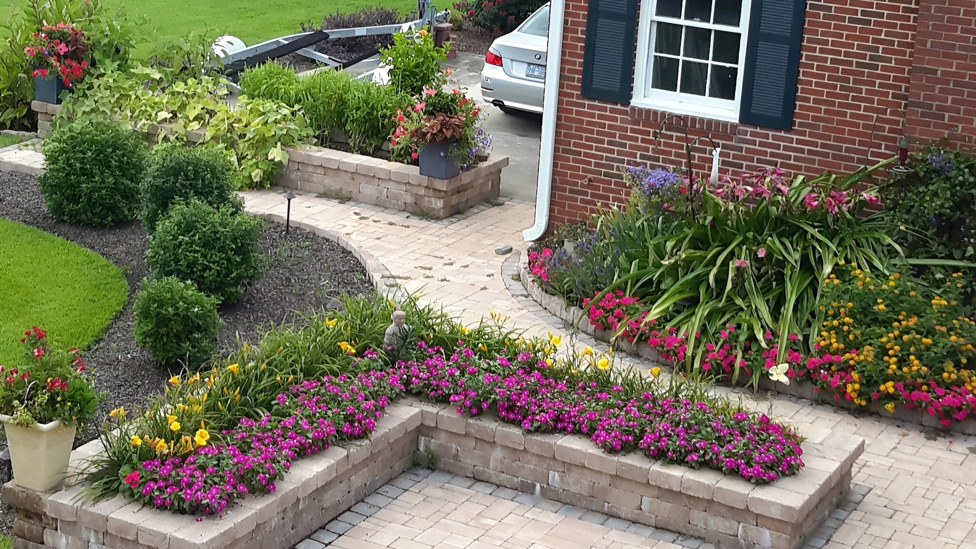 Colorful garden with flowers and brick patio.