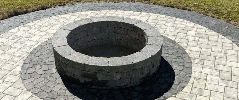 Stone fire pit on circular paved patio.