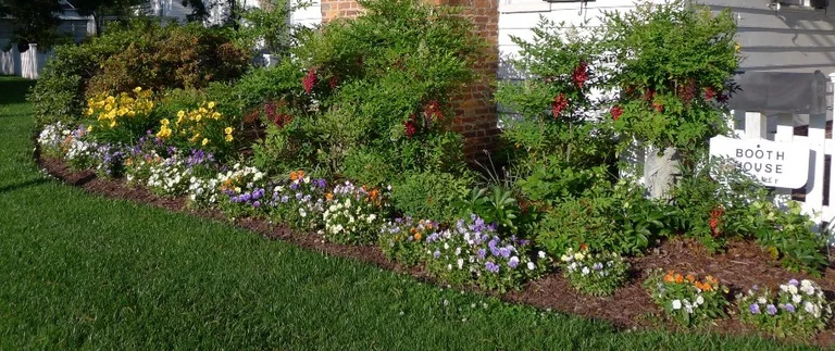 Colorful flower garden beside a brick house.