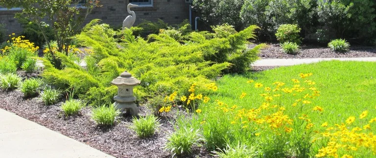 Lush garden with flowers and decorative statue.