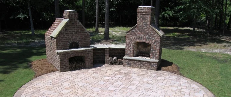 Outdoor brick fireplaces on stone patio.