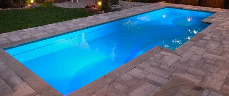 Illuminated rectangular swimming pool at night.