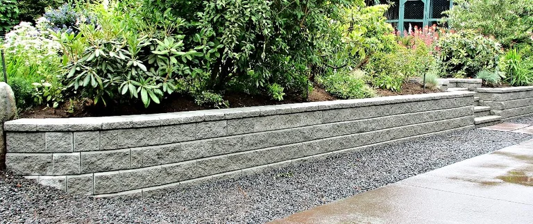 Stone retaining wall with lush greenery.