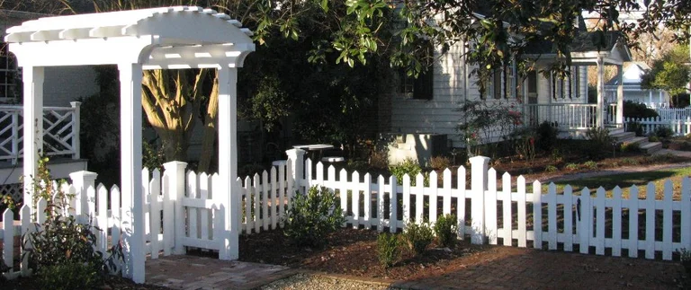White picket fence with garden and arbor.