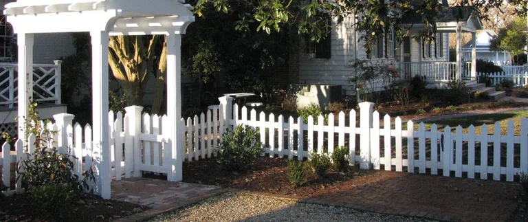 White picket fence with garden and arbor.