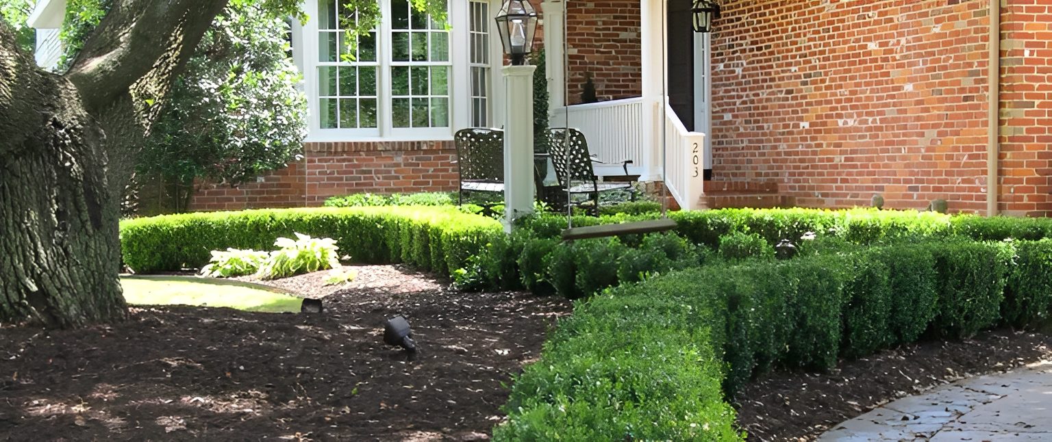 Brick house with manicured garden and bench.