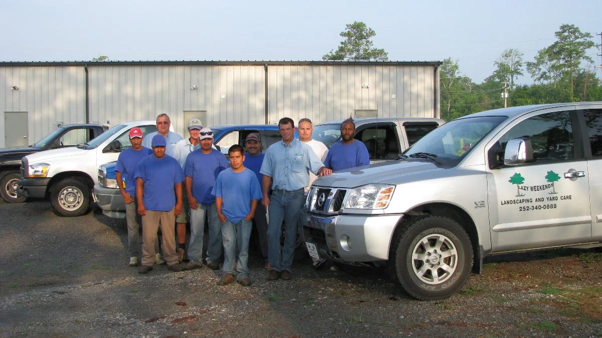 Group of workers standing by company vehicles.