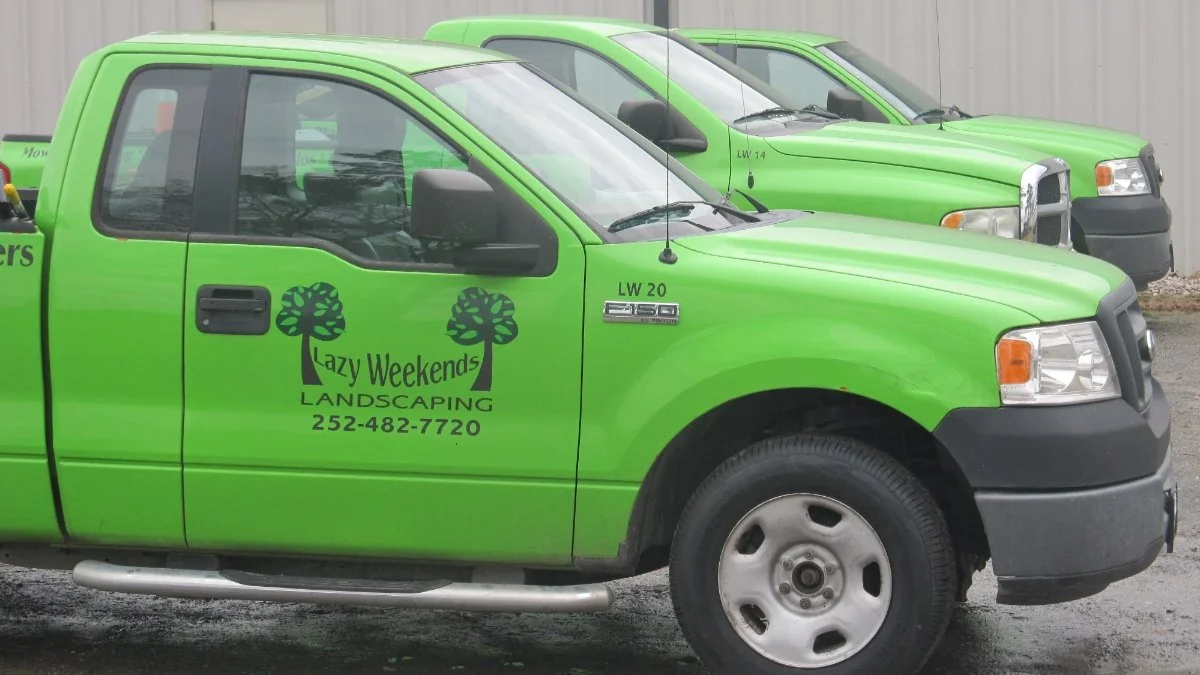 Green landscaping trucks parked in a row.