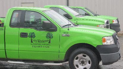 Green landscaping trucks parked in a row.