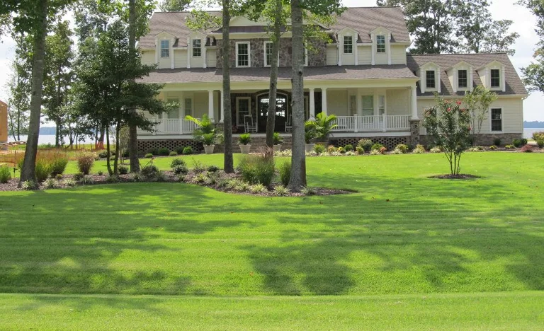 Large house with green lawn and trees.
