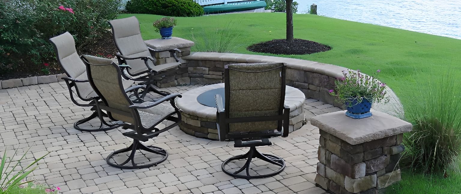 Patio chairs around a stone fire pit.