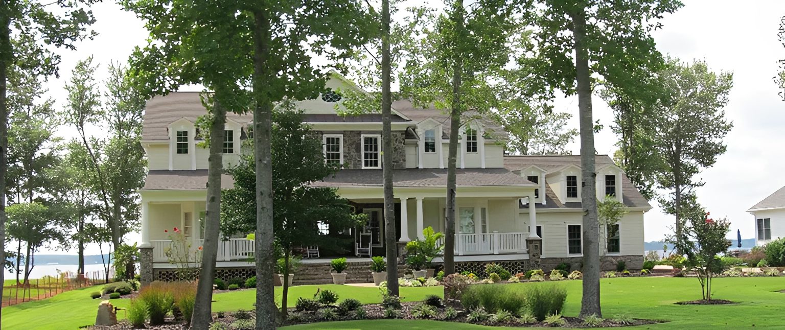 Large house with trees and green lawn.