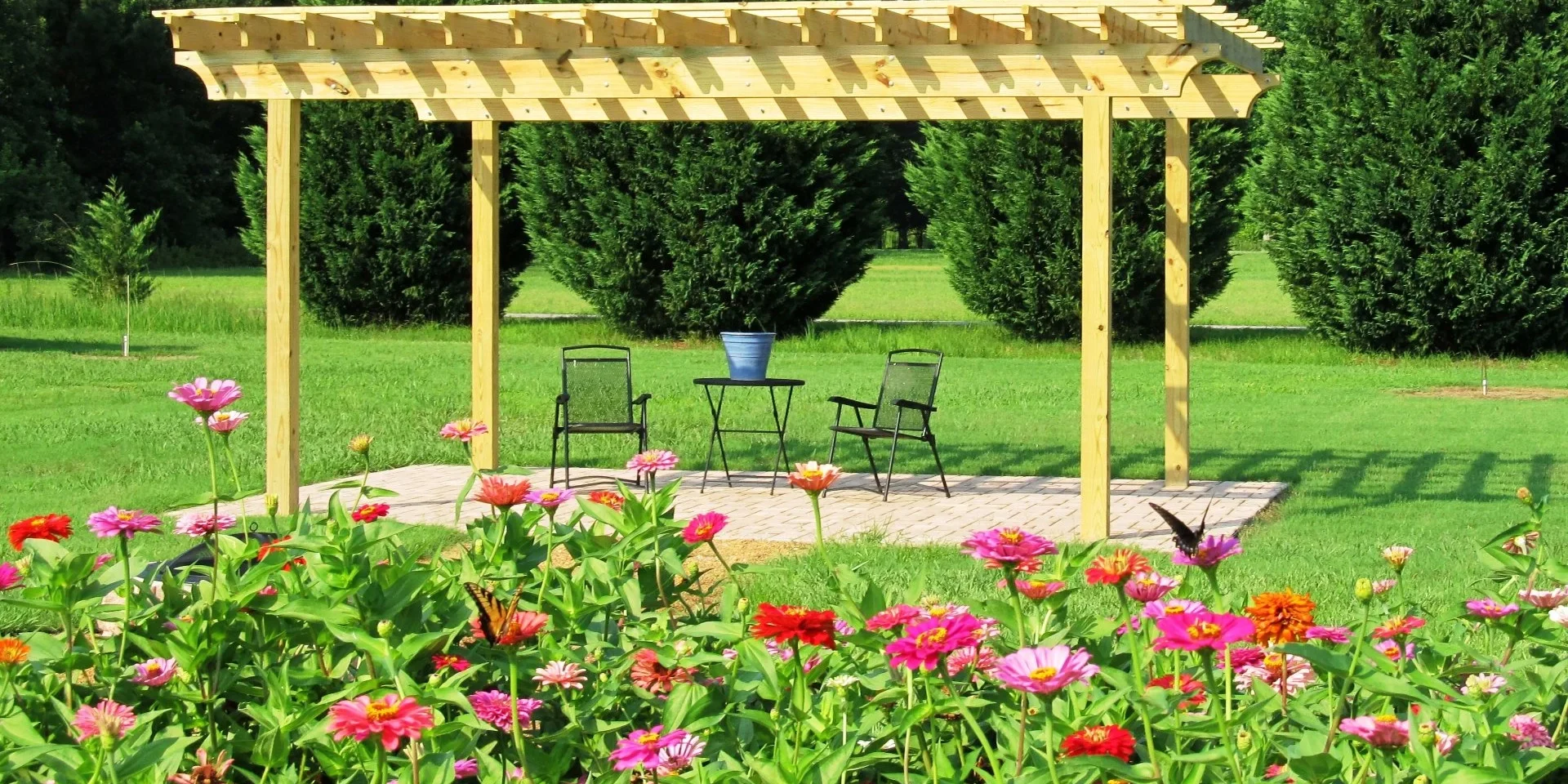 Garden pergola with chairs and flowers.